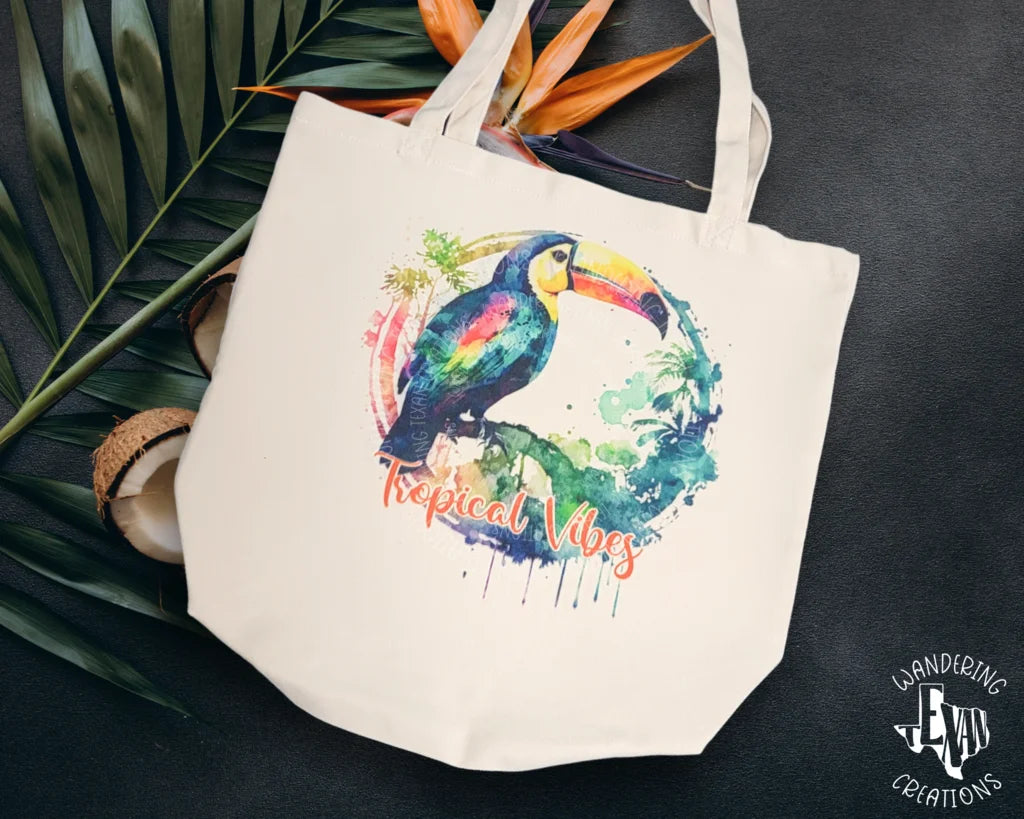 This Tropical Vibes Canvas Tote is a unique accessory, featuring a tropical vibes sublimation design with a toucan and watercolor background.