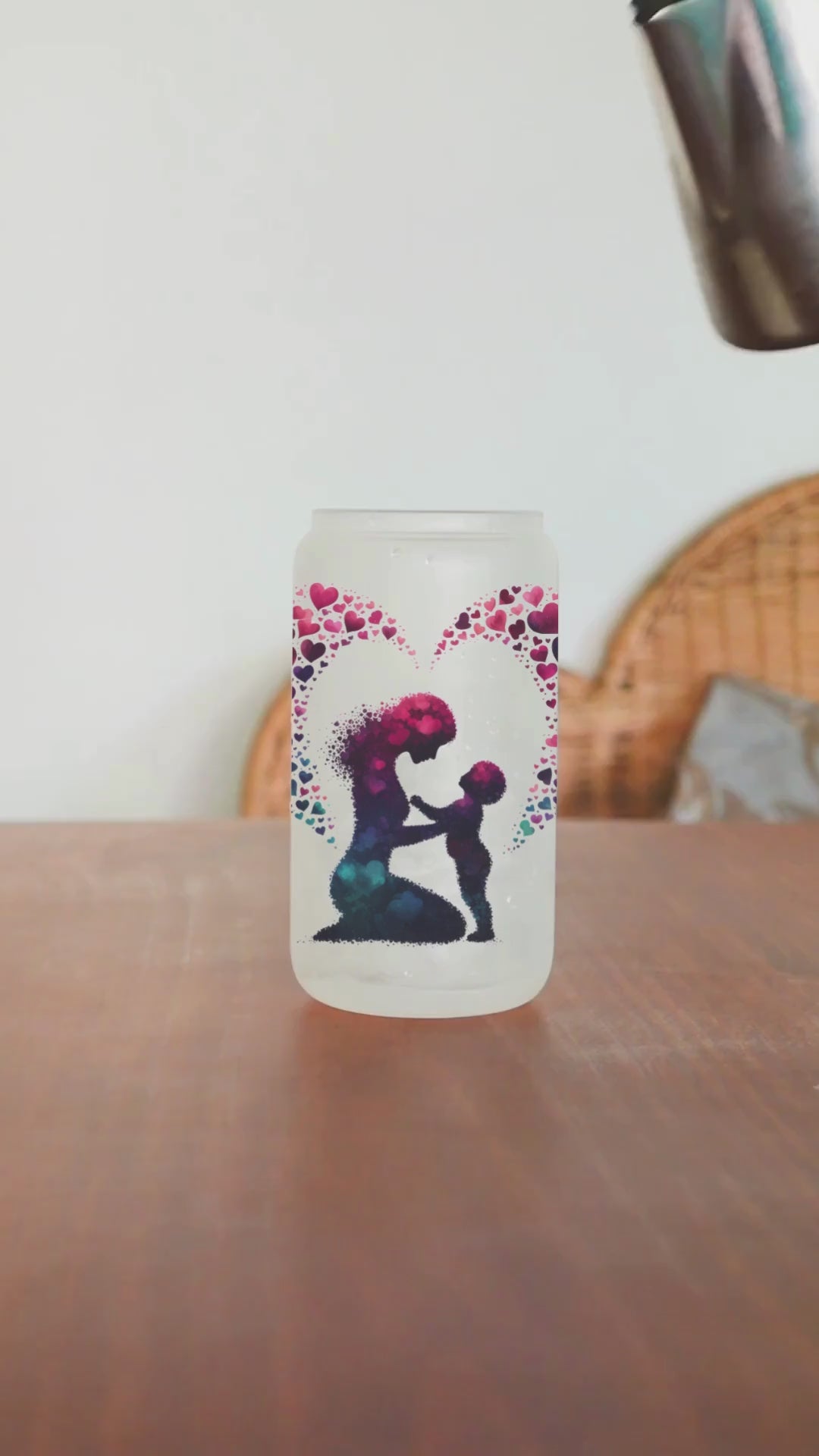 This frosted glass tumbler features a unique silhouette design of a mom and child made of overlapping hearts, with a heart surrounding both.